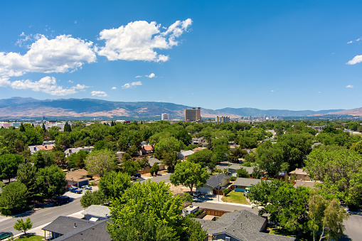 Aerial view of the Reno/Sparks Nevada downtown skyline district during summer with mature green trees and a bright blue sky with a few clouds.
