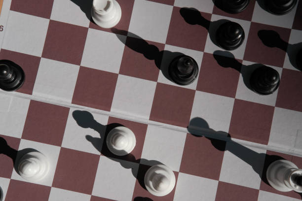 istock Chessboard and game figures. Blur and selective focus. Top view and shadows. 1409964322