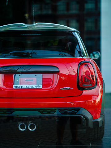 Toronto, Ontario, Canada- June 25, 2021. Chili red colour MINI COOPER in the dealers window display at East side of Toronto, Canada. This is the third generation model F56 JCW, since BMW took over iconic brand of MINI. MINI featured in the photo is John Cooper Works model, the most powerful 2 door version. For the first time, this compact car features engine build and designed by BMW, and packs even more power and torque than previous models since 2002 to present. Original design clues and themes are still present on this brand new model. Mini has been around since 1959 and has been owned and issued by various car manufacturers.