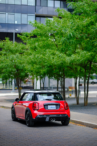 Toronto, Ontario, Canada- July 18, 2021. Chili red colour MINI COOPER on the streets of Toronto East side, Canada. This is the third generation model F56 JCW, since BMW took over iconic brand of MINI. MINI featured in the photo is John Cooper Works model, the most powerful 2 door version. For the first time, this compact car features engine build and designed by BMW, and packs even more power and torque than previous models since 2002 to present. Original design clues and themes are still present on this brand new model. Mini has been around since 1959 and has been owned and issued by various car manufacturers.