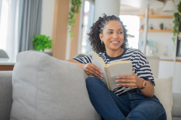 istock Happy woman reading book at home 1409969889