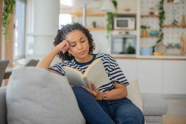 istock Happy woman reading book at home 1409969894