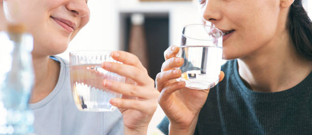 friends drinking a fresh glass of water at home stock photo