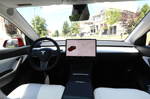 June 28, 2022 - Vaughan, Ontario, Canada: Brand new 2022 Tesla Model Y Dual Motor in red color with white and black interior. Modern electric vehicle. Environmentally-friendly car. Luxury electric crossover. Luxury electric SUV. Saving the planet by driving an electric vehicle. Modern and sleek car interior. Simple and beautiful design. Luxury vehicle.