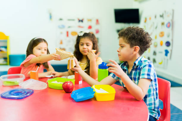 istock Kindergarten kids learning to share their lunch food 1409981287