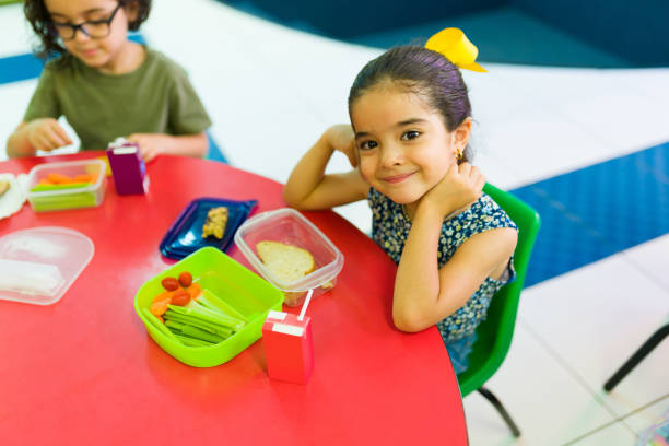 bella ragazza carina nella sua pausa pranzo all'asilo - child food school children eating foto e immagini stock