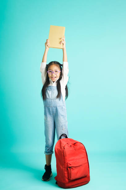 istock kid students girl smiling holding book, going to school. 1409983558