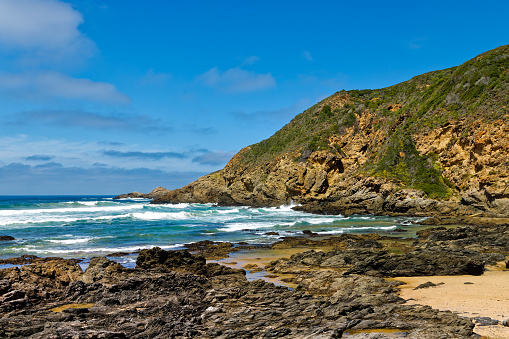 Seascape of rocky bay with waves and promontory near Herolds Bay, Garden Route, Western Cape, South Africa