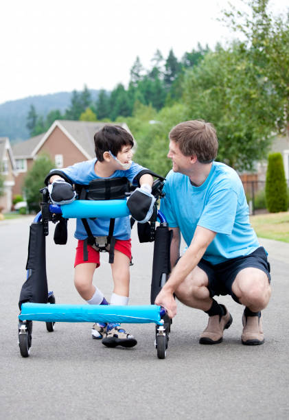 istock Father kneeling next to disabled son standing in walker 1409983749