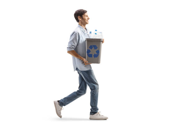 Young man walking and carrying a recycling bin with plastic bottles stock photo