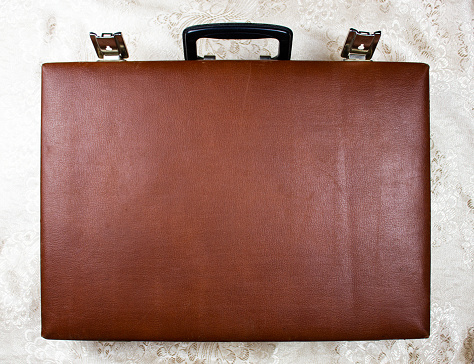The Old brown rare suitcase, leather case. Vintage briefcase suitcase with a handle made of genuine brown leather close-up.
