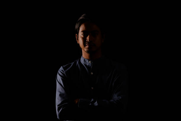 istock Young man portrait in high contrast dark background. 1409990393
