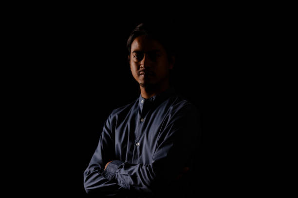 Young man portrait in high contrast dark background.