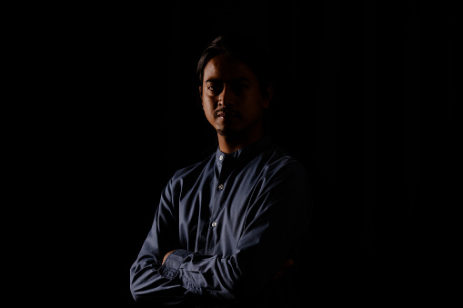Portrait of a handsome mature man looking at camera over black background. Senior bearded man standing in dark room. Closeup portrait of a sexy male model with lots of dark copy space