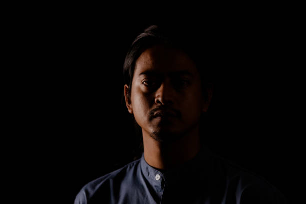 istock Young man portrait in high contrast dark background. 1409990397