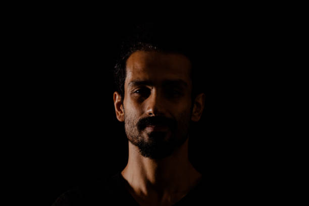 istock Young man portrait in high contrast dark background. 1409990521