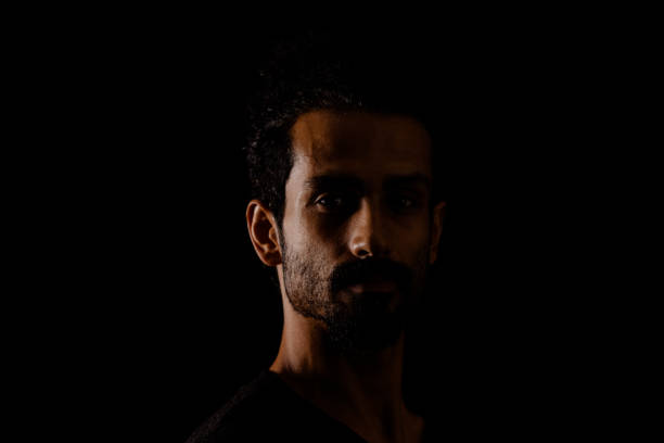 istock Young man portrait in high contrast dark background. 1409990524