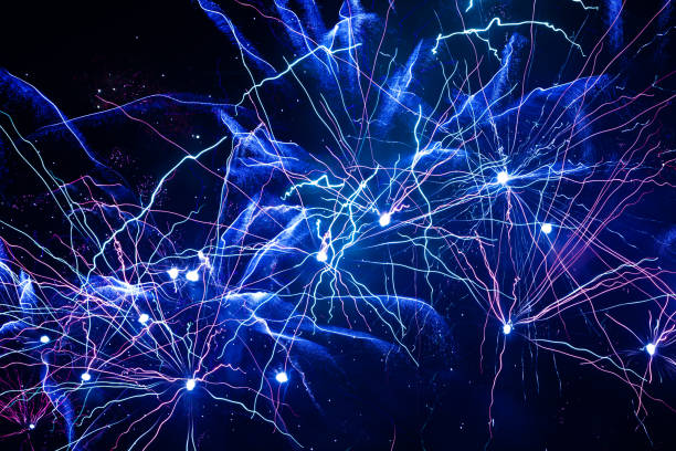 people in silhouette watch a colorful fireworks show, vertical frame