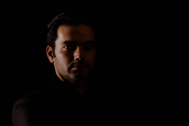 istock Young man portrait in high contrast dark background. 1409992354