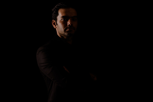 portrait of man shouting with open mouth. Lateral light was used. Photographed in a dark environment. It was shot in a studio environment with a full frame camera.