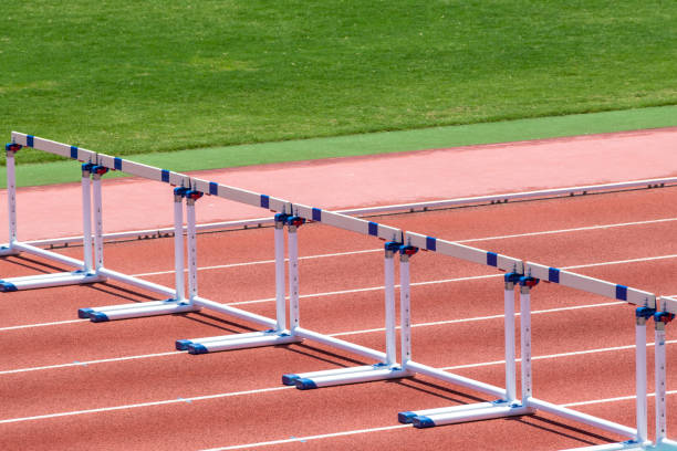 hürden auf den bahnen im leichtathletikstadion - hürdenlauf laufdisziplin stock-fotos und bilder