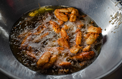 Bananas and sweet potatoes are battered and fried in a hot oil pan.