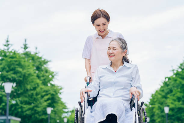 車椅子の女性とエプロンを着た若い女性 - 介護　日本 ストックフォトと画像