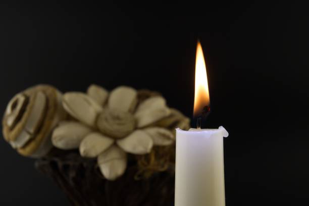 istock Candle flame and flowers against a black background 1410002172