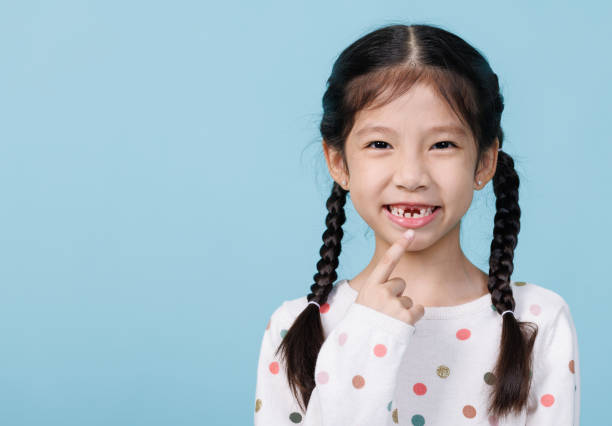 7 jahre altes kind hat einen losen zahn, zahnmedizin und gesundheitsvorsorgekonzept, leerer raum isoliert auf blauem hintergrund - 6 7 years stock-fotos und bilder