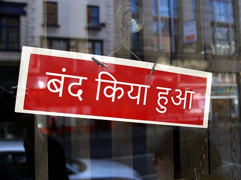 Closed sign in a shop window written in Hindi (translation: Closed)