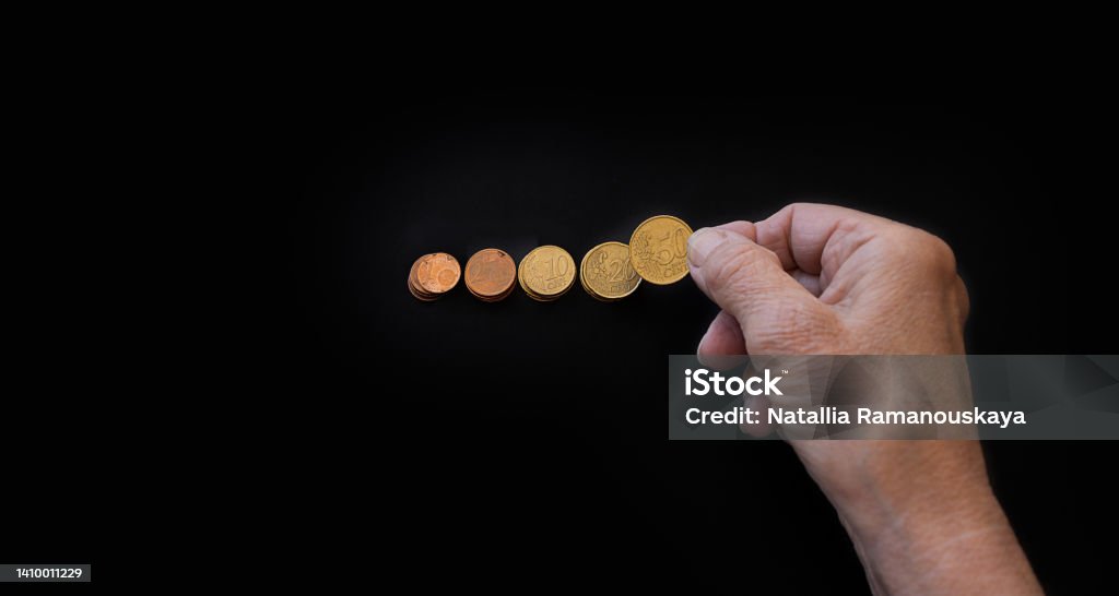 close-up, the hand of an elderly woman lays out coins on a black background close-up, the hands of the old woman put the coins in piles. Poster on black background with copy paste for text. The concept of poverty, small benefits for the elderly, financial crisis, low pensions Active Seniors Stock Photo