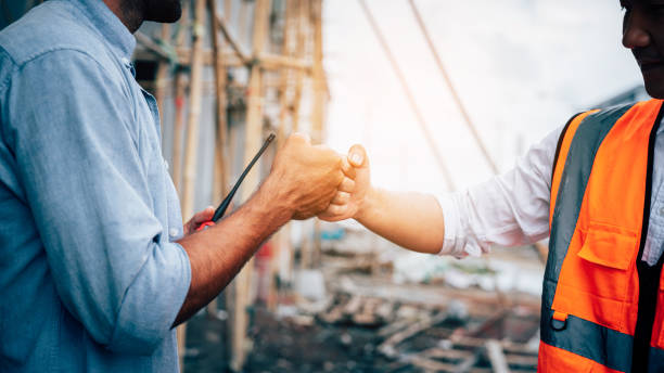 Portrait of Engineer construction workers shaking hands with deals on construction site. stock photo