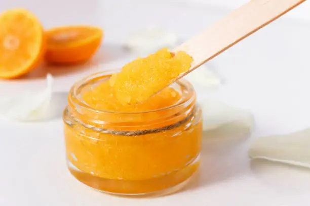 Sugar body scrub with ripe, juicy oranges on a white wooden table
