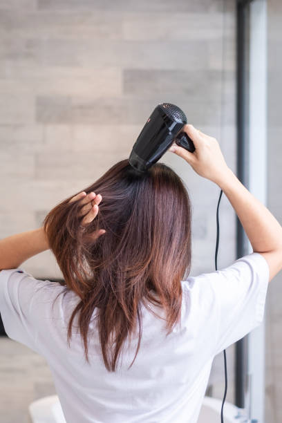 집이나 호텔에서 헤어 드라이어를 사용하는 젊은 여성. 헤어스타일과 라이프스타일 개념 - female hairdresser wet holding 뉴스 사진 이미지