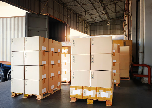 Packaging Boxes Stacked on Pallets Loading into Cargo Container. Shipping Trucks. Supply Chain Shipment. Distribution Supplies Warehouse. Freight Truck Transport Logistics.