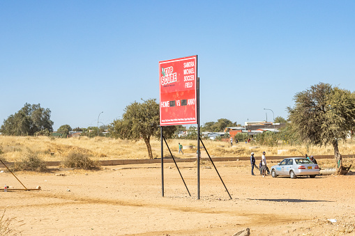 People visible around a car at the Samora Machel Soccer Field at Katutura Township near Windhoek in Khomas Region, Namibia. Samora Machel was the first President of Mozambique from its independence in 1975.
