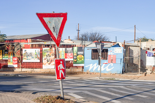 Give Way Sign at Katutura Township near Windhoek in Khomas Region, Namibia, with many commercial posters in the background.