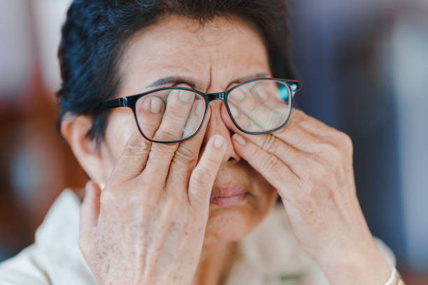 une femme âgée utilise sa main pour masser ses yeux en raison de la fatigue. et ont une vision floue. concept de problèmes de santé chez les personnes âgées. - dégénératif photos et images de collection