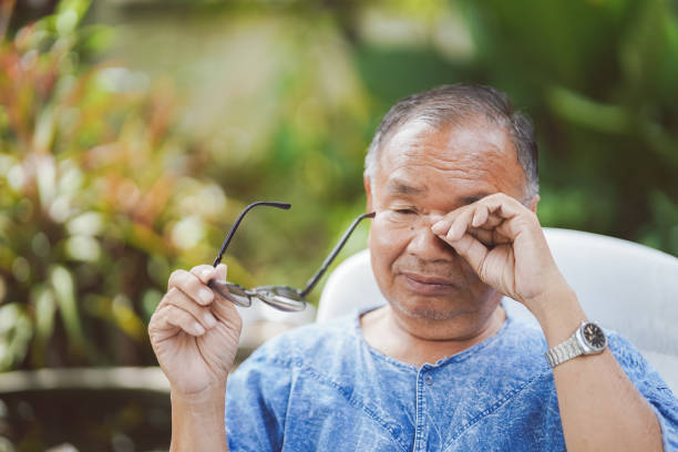 Elderly man rubbing his eyes while holding glasses due to overuse of the eyes, causing itching and irritation.