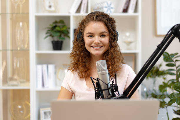 istock Young curly female recording podcast from home and talking into a microphone 1410024189