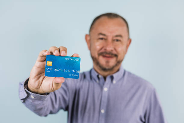 retrato de idoso latino segurando cartão de crédito em fundo azul no méxico na américa latina - mexico only men senior men mature men - fotografias e filmes do acervo