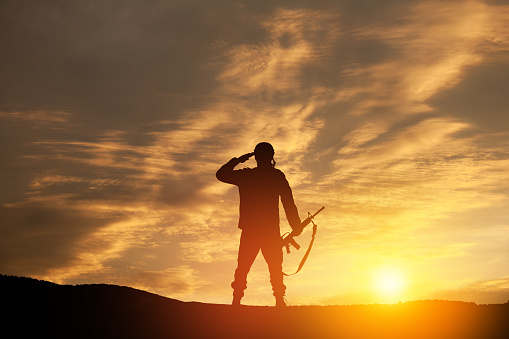 Silhouette of soldier standing against the backdrop of a sunset. Greeting card for Veterans Day, Memorial Day, Independence Day. USA celebration. Concept - patriotism, protection, remember honor.