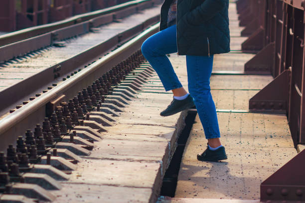 A woman steps over the rails in an unidentified place for passage.