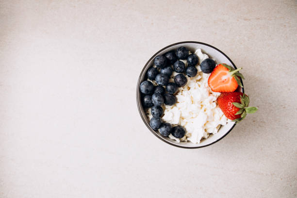 istock Cottage cheese with fresh blueberries and strawberries in a plate on a light background. Healthy breakfast 1410030022