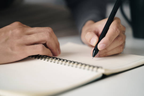 istock left handed man writes in a notebook on the table 1410037122