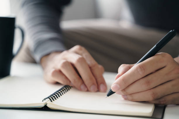 istock left handed man writes in a notebook on the table 1410037126