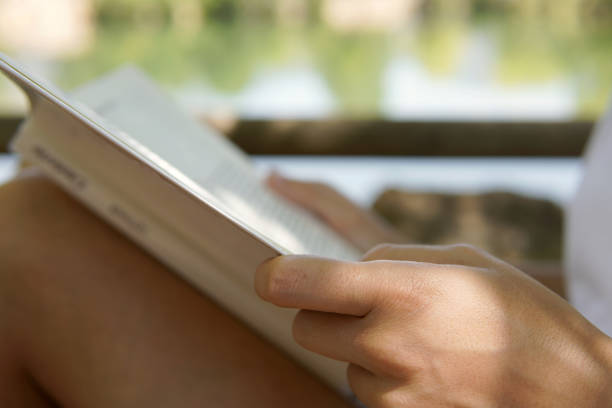 istock Close up of a hand with a book in a park. Selective focus 1410037384