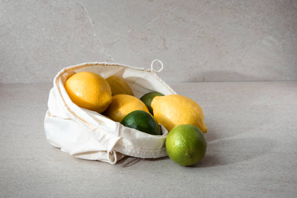 istock Fresh lemons and limes in a fabric bag on a light stone background 1410037565