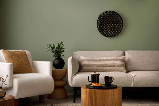 istock Modern composition of living room interior with green wall, grey sofa with pillow. White armchair with brown pilow, wooden coffe table with black accessories. Black ornament on wall.  Template. 1410040251