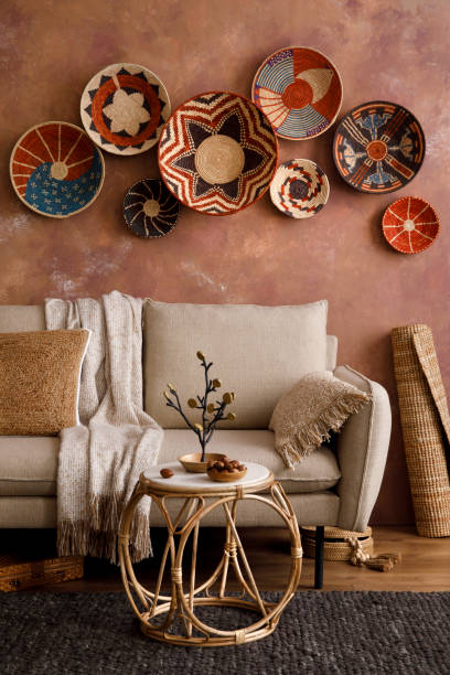 istock The stylish boho composition at living room interior with design beige sofa, coffee table, table, wicker baskets and personal accessories. Beige and white pillows. Cozy apartment. Template. 1410040641